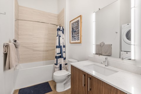 A modern bathroom with a white toilet, a white sink, and a white bathtub.