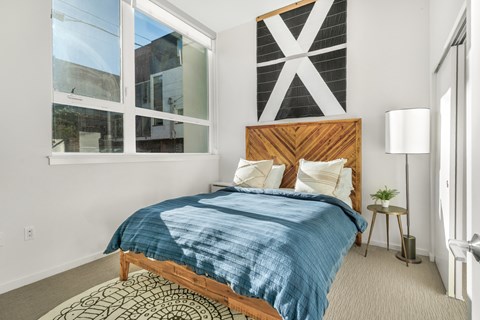 A bedroom with a bed, a lamp, and a window.