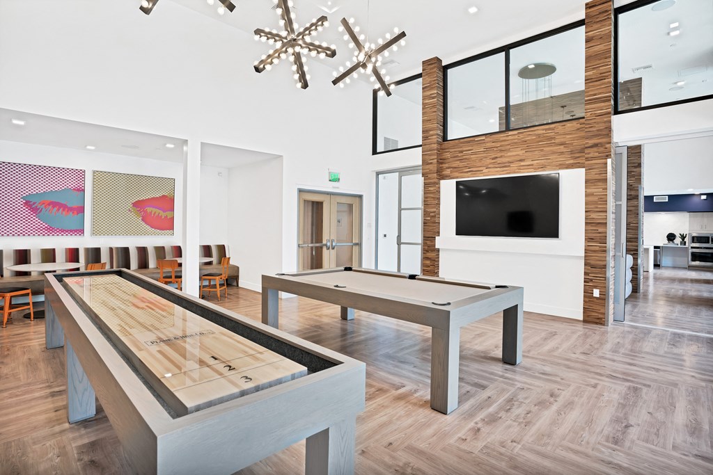 a game room with a shuffleboard table and a television