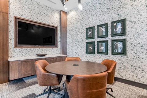 A conference room with a table, chairs and a television.
