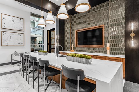 A modern kitchen with a white countertop and black chairs.