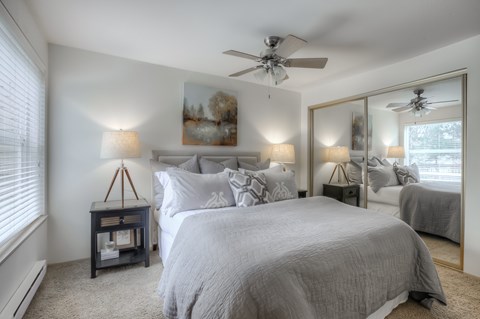 A bedroom with a large bed and a ceiling fan.