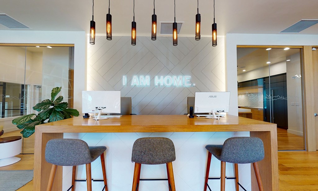 a front desk with three stools in front of a counter with two computers