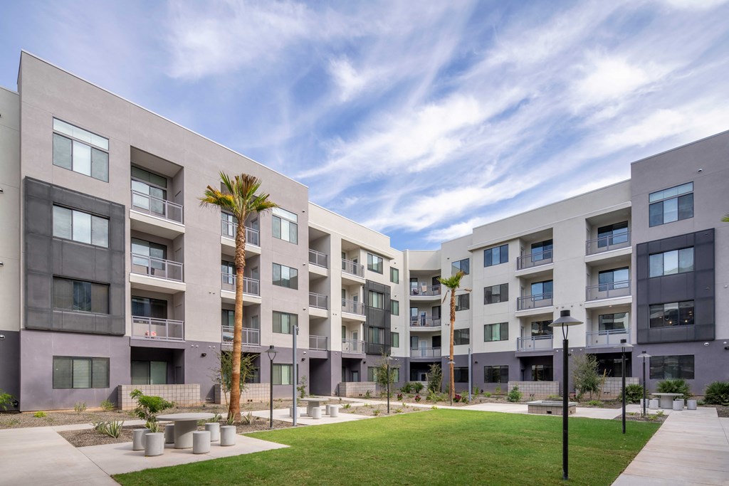 a group of apartment buildings with grass and palm trees