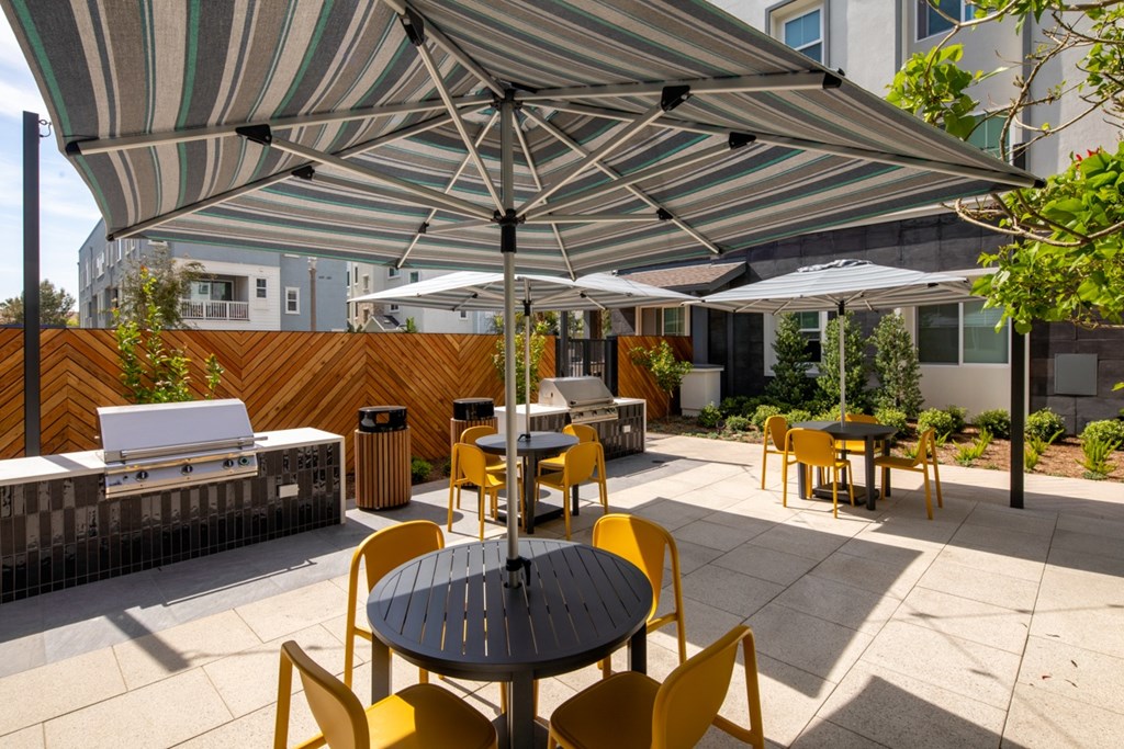 A patio with a table and chairs under a striped umbrella.