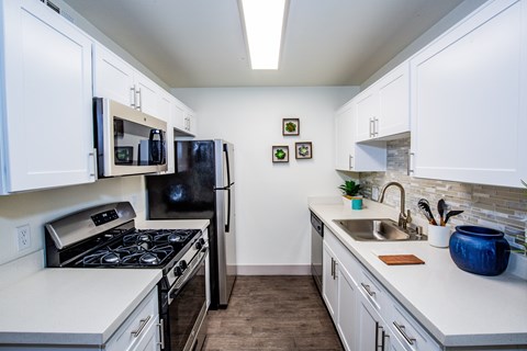 A kitchen with white cabinets and a black refrigerator.