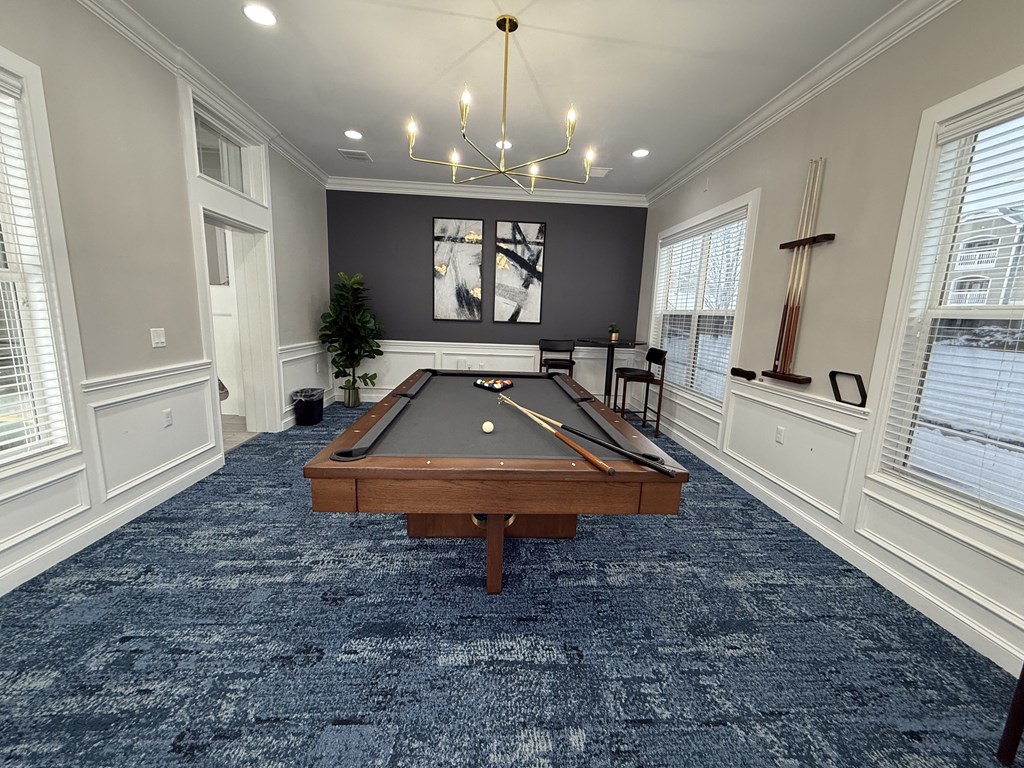 A pool table in a room with a chandelier and a painting on the wall.