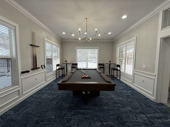 A pool table is in the middle of a room with a blue carpet.
