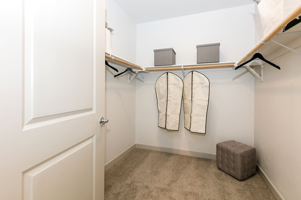 a walk in closet with a pair of folded towels and a stool