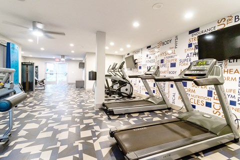 a workout room with treadmills and a wall covered in graffiti