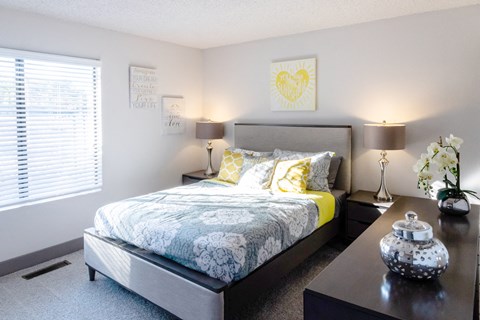 a bedroom with a bed and a night stand and a window