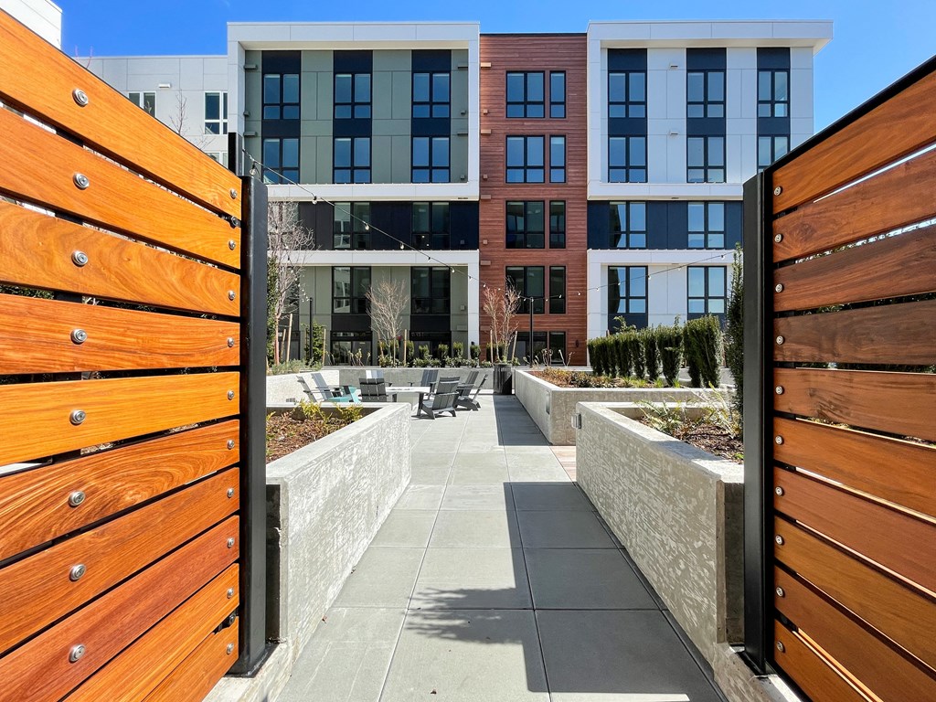 a view through a wooden gate into a courtyard with buildings