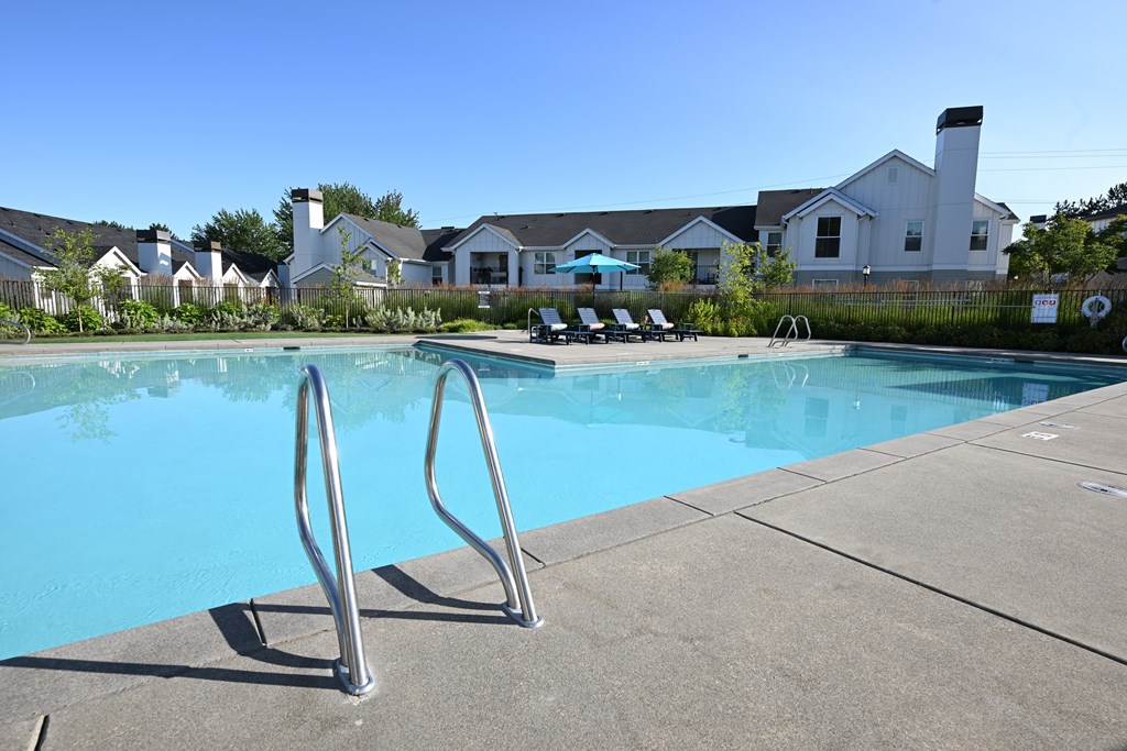 A swimming pool with a diving board in front of a residential area.