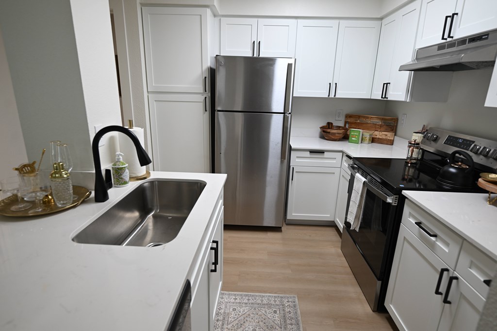 A kitchen with a stainless steel refrigerator and black oven.