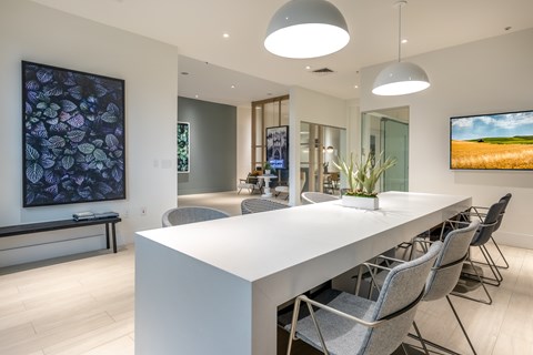 A modern conference room with a long white table and grey chairs.