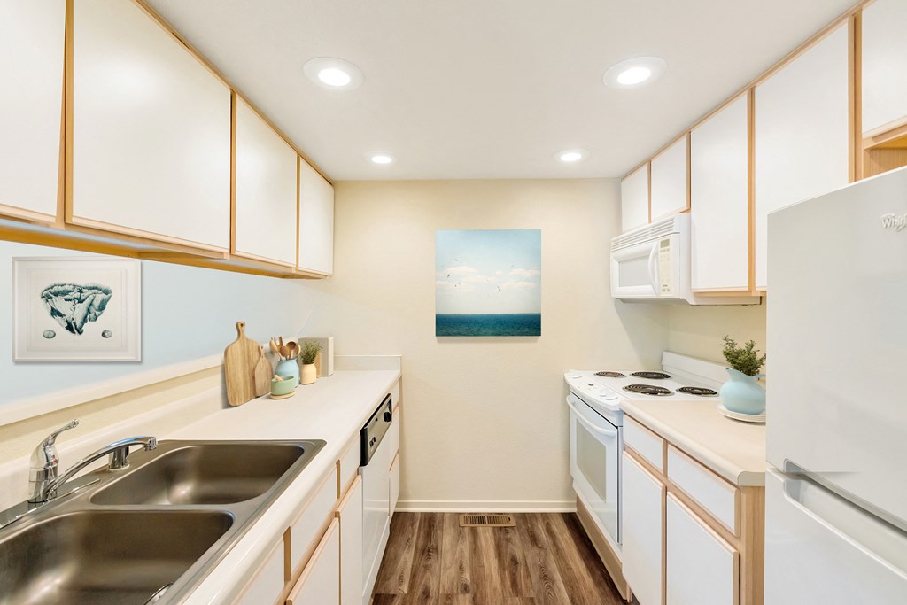 a kitchen with white appliances and wooden cabinets and a sink