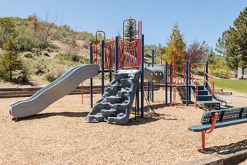 a playground with slides and benches in a park