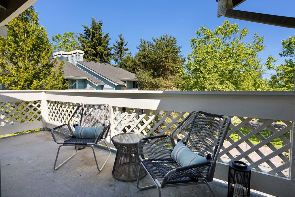 A patio with a white railing and two chairs.