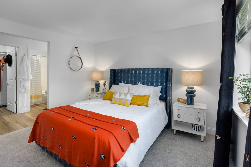 A bedroom with a white bed and orange bedspread.