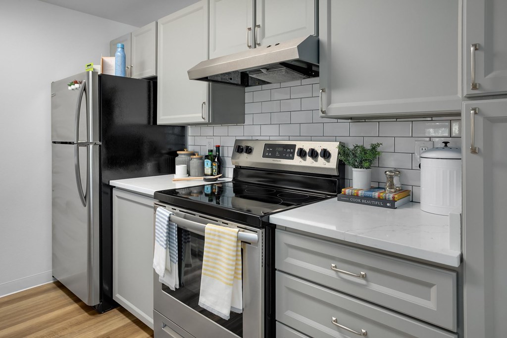 A modern kitchen with a black refrigerator, stainless steel oven, and white countertops.