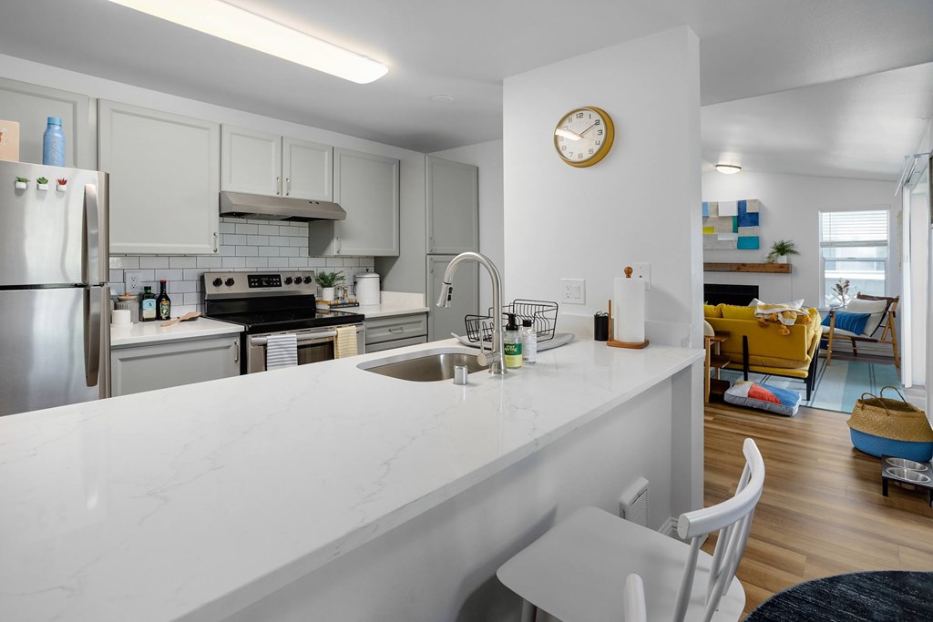 A kitchen with a white counter top and a clock on the wall.