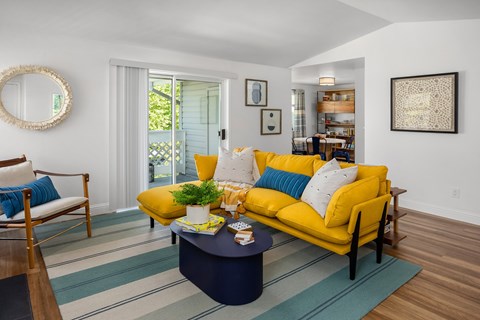 A living room with a yellow couch and a blue coffee table.