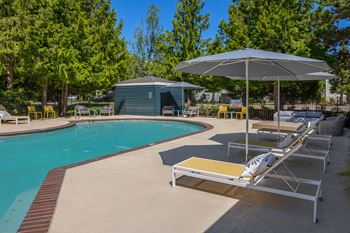 A pool with sun loungers and umbrellas.