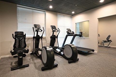 A gym with elliptical machines and a treadmill.