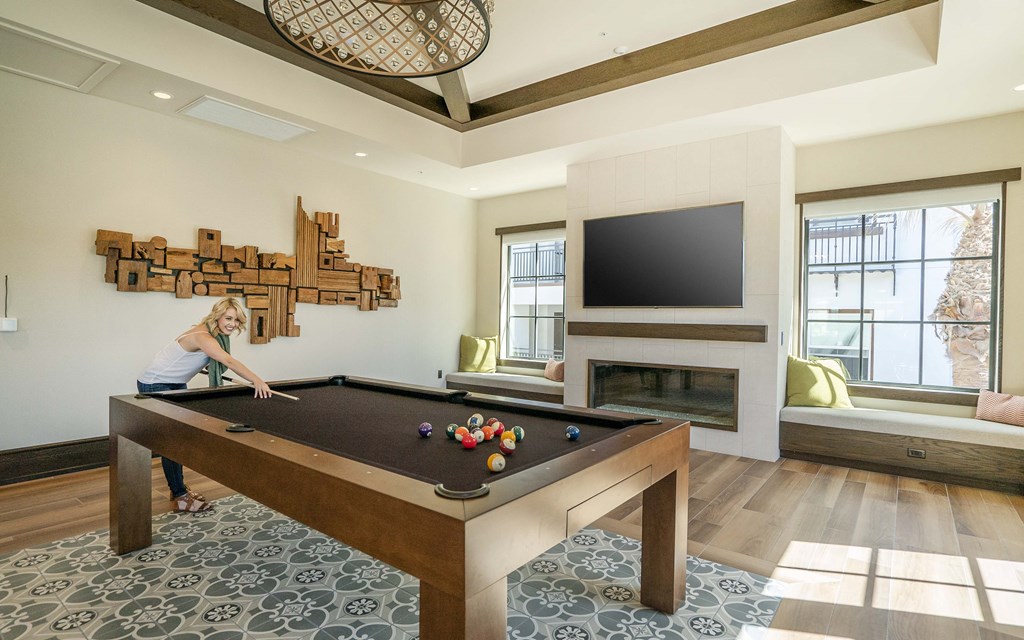 a woman playing a pool table in a living room with a tv