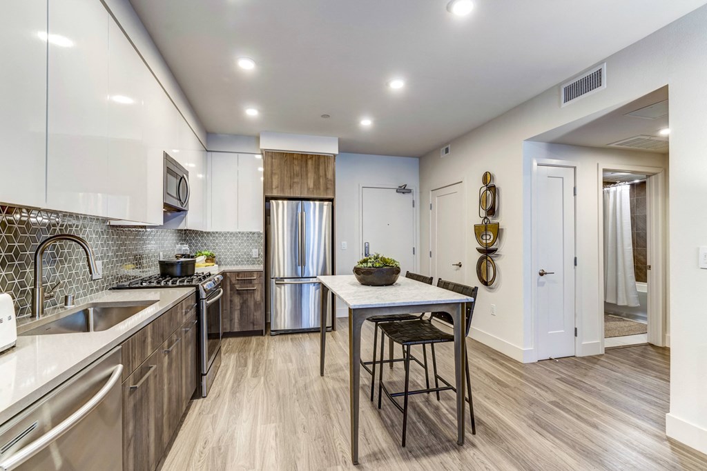 a kitchen with stainless steel appliances and a table with two stools