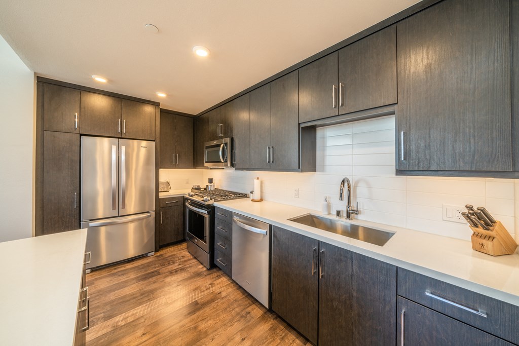 A modern kitchen with dark wood cabinets and stainless steel appliances.