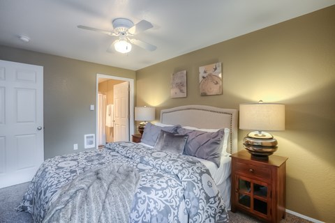 A bedroom with a bed, nightstand, and a ceiling fan.