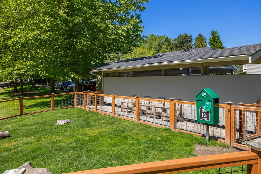 A green mailbox sits on a wooden fence in front of a house.