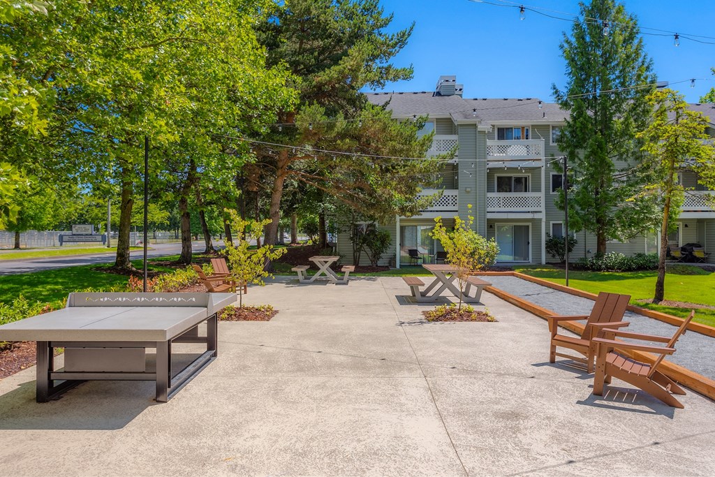 A concrete patio with a table and chairs in front of a building.
