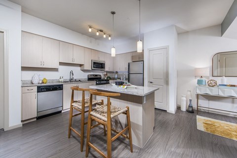 a kitchen with white cabinets and a counter top with two stools