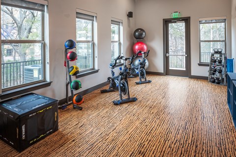 A gym room with exercise equipment and a wooden floor.