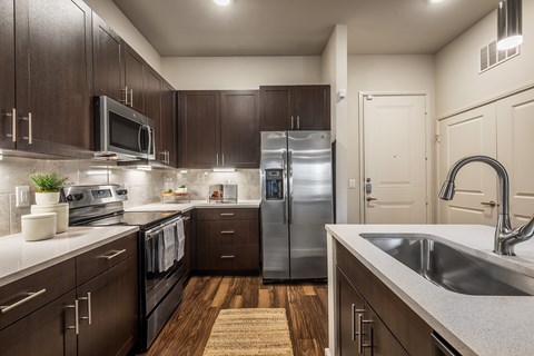 A kitchen with dark wood cabinets and stainless steel appliances.