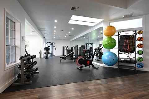 A gym with a variety of equipment including weights, exercise balls, and resistance bands.