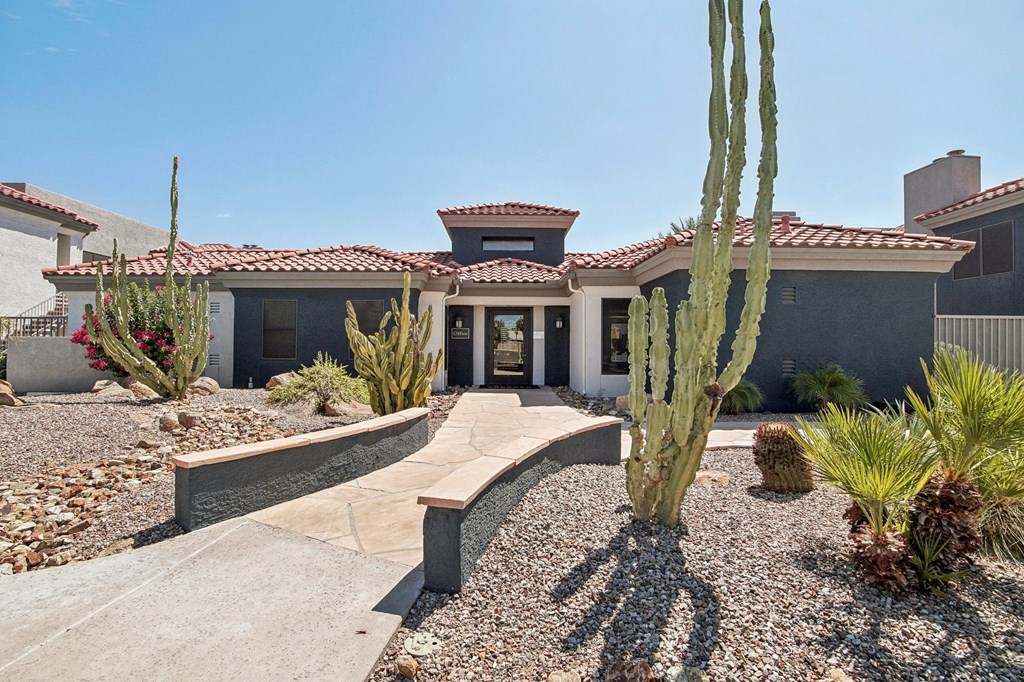 a house with a pathway and cactus in front of it