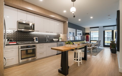 A modern kitchen with a wooden table and stools.