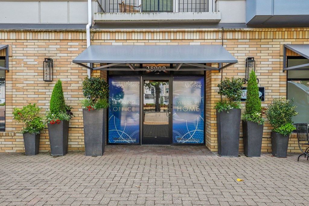 the front of a brick building with doors and potted plants