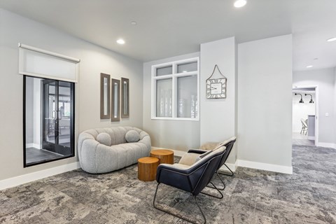 a lounge area with a white couch and chairs and a large window