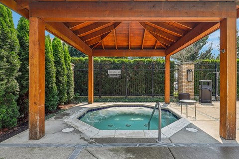 a hot tub is under a wooden pavilion next to a pool
