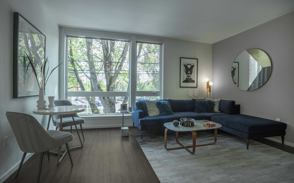 a living room with a blue couch and a table and a large window