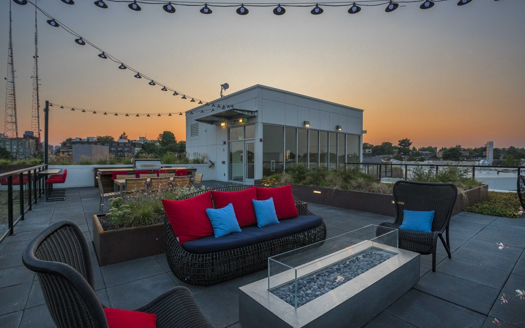 a rooftop patio with furniture and a building in the background