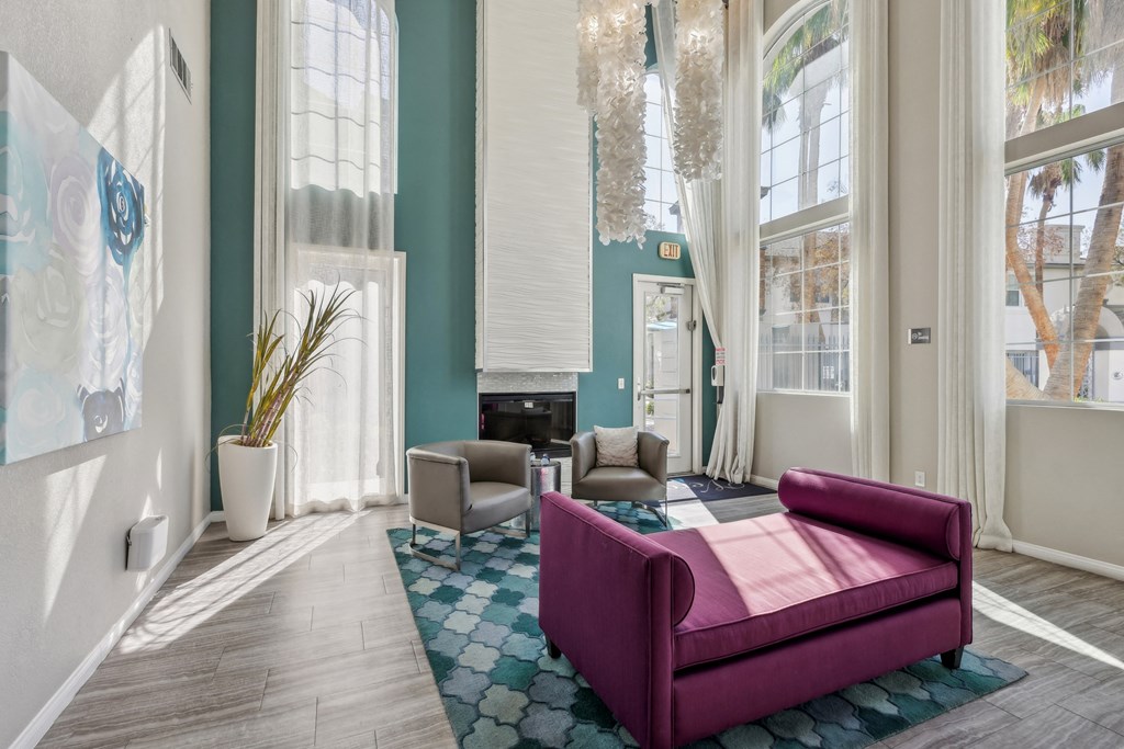 a social room with a purple couch and chairs and a fireplace