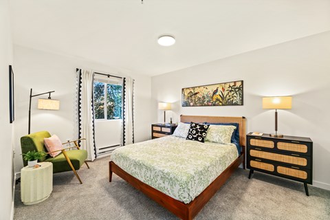 A bedroom with a bed, a chair, and a nightstand.