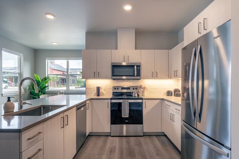 a modern kitchen with stainless steel appliances and white cabinets