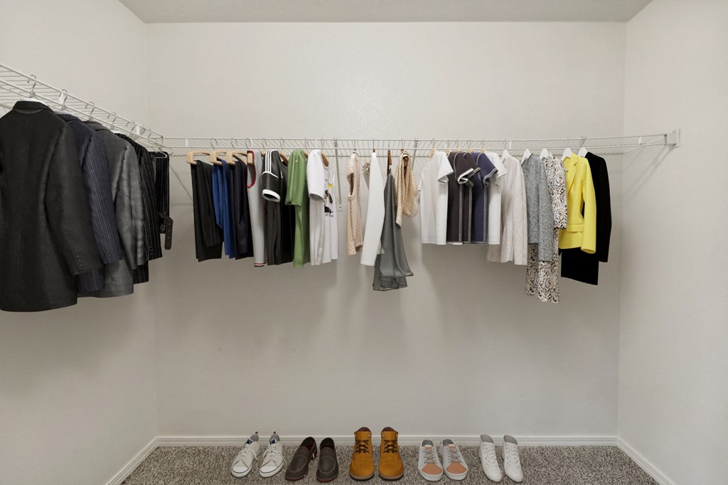 a closet with clothes hanging on a rack and shoes on the floor