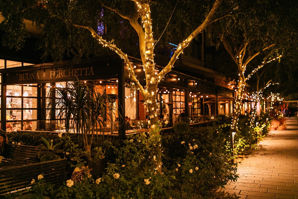 A restaurant named Buona Ferretti is lit up at night with lights and decorations.